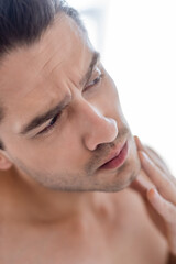 close up view of man touching chin in bathroom.