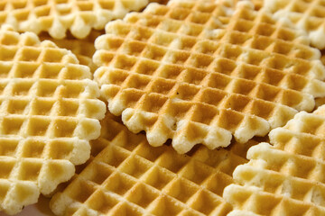 Pile of round Belgian waffles as background, selective focus. Thin golden waffled cookies.