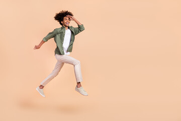 Fototapeta na wymiar Full length body size view of attractive cheerful guy jumping running look search future isolated over beige pastel color background