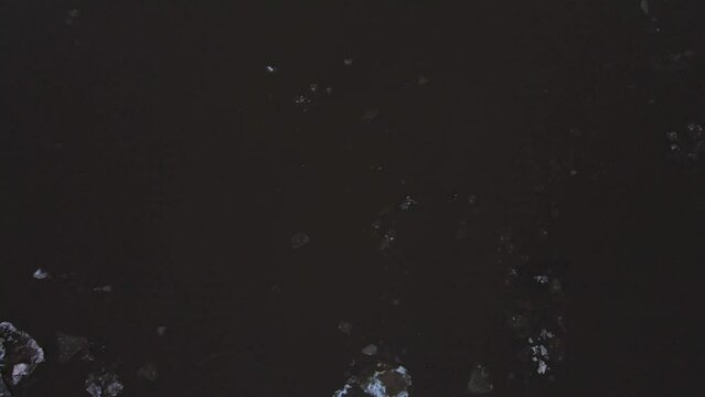 Dirty white ice floes float along the gloomy river. Spring, snow melts, ice drift, flood and flood of the river. Evening, cloudy weather, soft warm light. UHD 4K