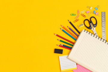 Top view notebooks and accessories studying in the library at school yellow background idea...