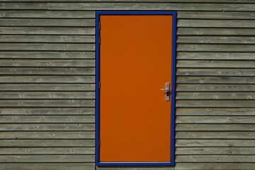 Orange door with blue frame in wooden house wall, use: background, copy space (horizontal), Zandvoort, North Holland, Netherlands - obrazy, fototapety, plakaty