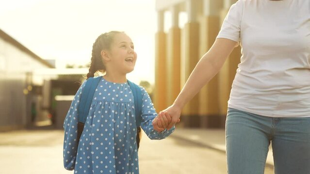 back to school. mom and daughter a go hand in hand to school for lesson. education training support concept. child walk to school with a backpack. daughter and mom rush to school. family sun day