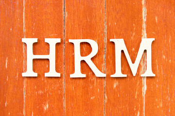 Alphabet letter in word  HRM (Abbreviation of human resource management) on old red color wood plate background