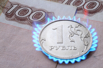 Russian coin with a face value of 1 ruble lies on a banknote. Translation of the inscriptions on the coin: "1 ruble". photomontage: burning coin.