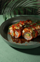 Unamaki with mango and red fish on a green plate among palm branches