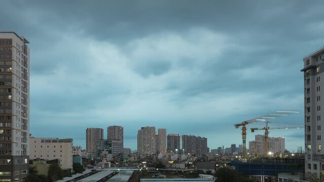 day to night time lapse of residential high rise buildings with working cranes on an adjacent construction site