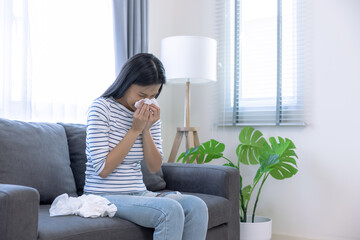 Young Asian woman sick with a cold, She sneezed and had a runny nose.