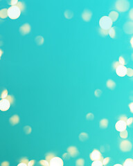 Christmas bright gold colors bokeh different sizes around the frame on vibrant cyan blurred background. Holiday template and shiny greeting concept with copy space.