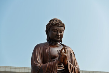 Wooden Buddha statue under blue sky - Powered by Adobe