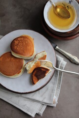 Japanese fluffy pancakes in a plate on the dining table with a cup of coffee and a bowl of honey. Light quick lunch.