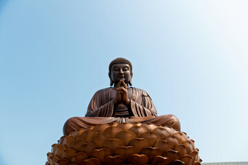 Fototapeta premium Wooden Buddha statue under blue sky