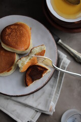Japanese fluffy pancakes in a plate on the dining table with a cup of coffee and a bowl of honey. Light quick lunch.