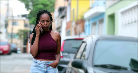 Black African woman talking on phone outside, candid mix race lady listening in conversation