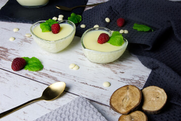 Pudding dessert with raspberry and mint on wooden floor. Near the candle.