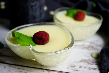 Pudding dessert with raspberry and mint on wooden floor. Near the teaspoon.