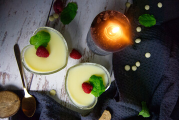Pudding dessert with raspberry and mint on wooden floor. Near the candle.