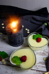 Pudding dessert with raspberry and mint on wooden floor. Near the candle.