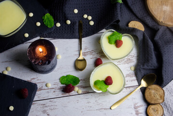 Pudding dessert with raspberry and mint on wooden floor. Near the candle.