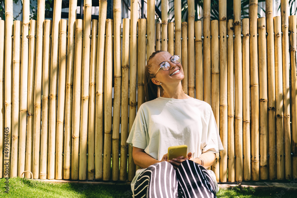 Poster cheerful travel blogger in trendy spectacles smiling and rejoicing while creating content text for n