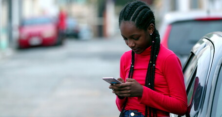 Black African girl texting on cellphone outside, Teenager on social media
