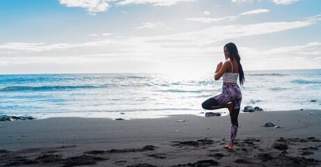 Fototapeta na wymiar woman in sport clothes practicing yoga and meditating on beach in morning