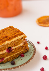 A piece of a honey cake with red berries, on white background. Orange colored cake