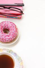 Top view photo of workplace glasses, notebook, pen , cup of coffee and plate donut on white background with copy space
