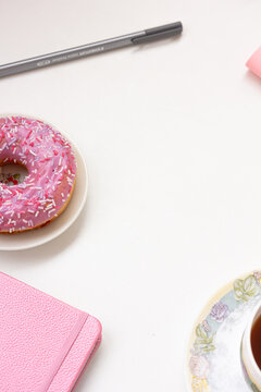Top view photo of workplace glasses, notebook, pen , cup of coffee and plate donut on white background with copy space