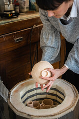 Obraz premium Female artisan putting ceramics in the kiln
