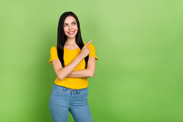 Photo of thoughtful pretty lady dressed yellow t-shirt pointing looking empty space isolated green color background
