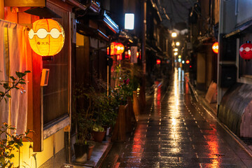 Obraz premium Red lantern illuminates entryway on dark Japanese street after rain