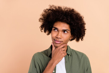 Fototapeta na wymiar Portrait of attractive bewildered smart clever wavy-haired guy touching chin overthinking isolated over beige pastel color background