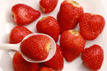 A close-up strawberry in a spoon, in the background other strawberries