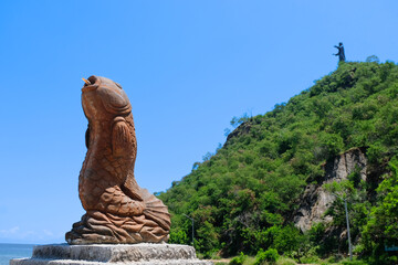 The popular landmark of Cristo Rei Jesus Christ statue with a tropical fish sculpture at the beach in Dili, Timor Leste