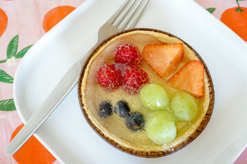Yummy fruit tart on white plate with fork. Tasty desert with berries, grapes and a natural glaze. Sweet tooth concept.
