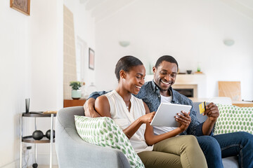 Mature black couple doing online shopping with credit card card at home - Powered by Adobe