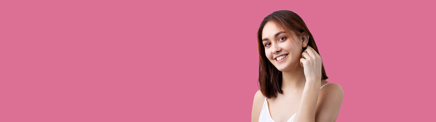 Fototapeta premium Beautiful smiling woman with clean skin, natural make-up and white teeth on a Pacific Pink background