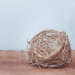 Real estate buying and leasing concept, home finance concept, Empty little birds nest isolated on a wooden floor.