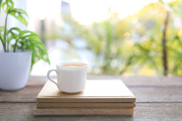 Tea cup and brown kraft notebooks and Window Monstera obliqua leaf plant