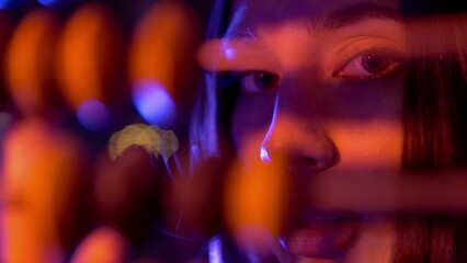 Close-up of a girl counting on old wooden accounts under neon light. Night club. Beautiful compositions with people in neon light. A model girl poses for the camera under a neon light.