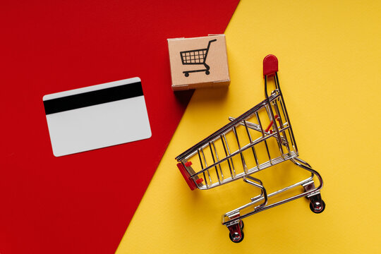 Shopping cart, box and credit card on a colorful background close-up