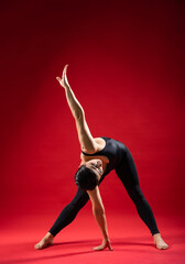 beautiful static poses. pilates on red background Woman in black sportswear. gymnastic poses