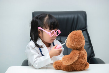 Portrait of cute asian little girl in doctor uniform working on the desk on white background,Child playing doctor with patient