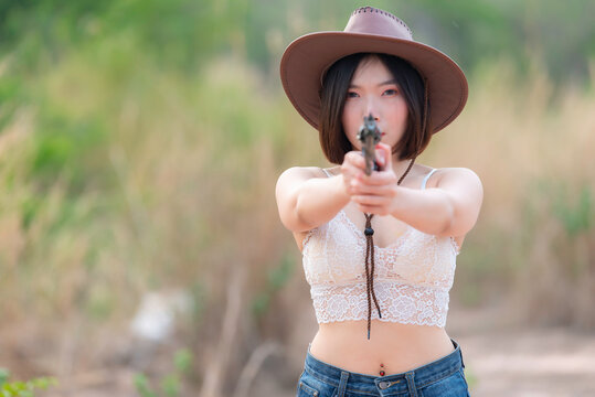 Portrait of asian woman wear cowgirl charactor at the field,Cowboy festival concept,Sexy lady pose for take a picture,Thailand people