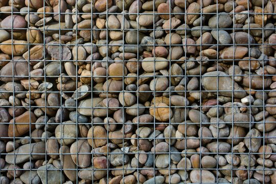 Gabions small architectural decoration of smooth stones in a metal mesh close-up