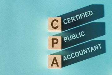 Wooden cubes building word CPA - abbreviation of certified public accountant - with shadows on...