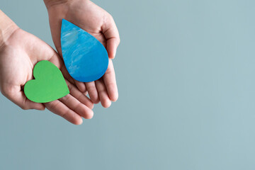 Hands holding green heart and water drop concept of save water save the world.