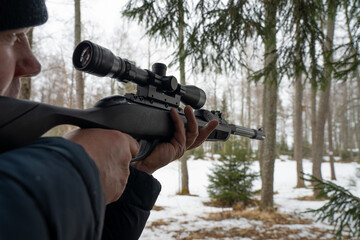 A man with a rifle in the spring forest, the hunter holds a rifle and waits for prey, the hunter shoots