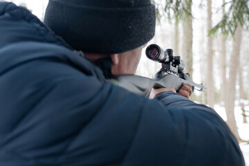 A man with a rifle in the spring forest, the hunter holds a rifle and waits for prey, the hunter shoots